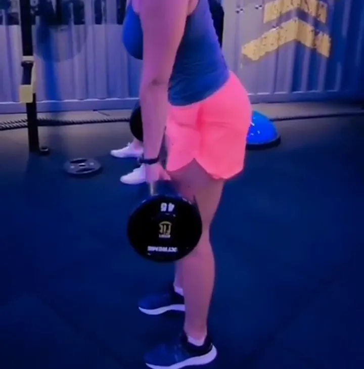 Jacqueline Junqueira treinando perna com anilha na academia